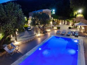 uma piscina à noite com cadeiras e guarda-sóis em Athiri House Villa Corfu em Spartýlas
