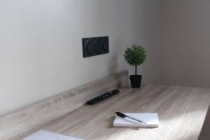 a pen and paper on a wooden table with a plant at Résidence "Le Vélodrome" in Maubeuge
