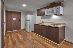 a kitchen with a white refrigerator and wooden cabinets at Extended Suites Saltillo Galer&iacute;as in Saltillo