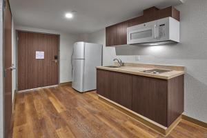 a kitchen with a white refrigerator and wooden cabinets at Extended Suites Saltillo Galerías in Saltillo