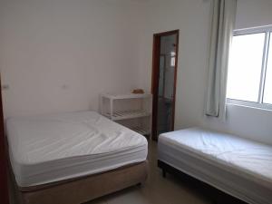 - une petite chambre avec 2 lits et une fenêtre dans l'établissement Casa Nova com Piscina 3 quartos, à Guaratuba