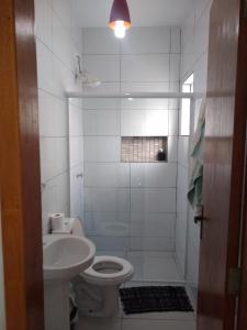 La salle de bains blanche est pourvue de toilettes et d'un lavabo. dans l'établissement Casa Nova com Piscina 3 quartos, à Guaratuba