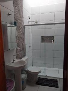 La salle de bains est pourvue d'un lavabo, de toilettes et d'une douche. dans l'établissement Casa Nova com Piscina 3 quartos, à Guaratuba