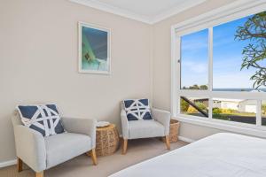 ein Schlafzimmer mit einem Bett und zwei Stühlen und einem Fenster in der Unterkunft Seahaven Gerringong in Gerringong
