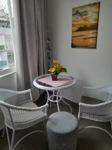 a table with chairs and a vase with flowers on it at Quadra Praia, Posto 4, Split, smarttv Cabo, wifi , 35m2 in Rio de Janeiro