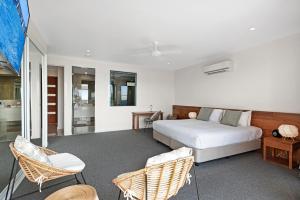 a bedroom with a bed and wicker chairs at Hidden Cove on Hamilton Island by HIHA in Hamilton Island