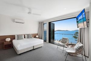 a bedroom with a bed and a large window at Hidden Cove on Hamilton Island by HIHA in Hamilton Island