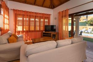 uma sala de estar com dois sofás brancos e uma televisão em Villa Helen - Heated Pool Wifi SmartTV Barbecue em Corralejo