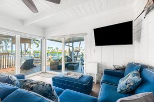a living room with blue couches and a flat screen tv at A Wave From it All in Key Colony Beach
