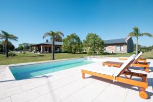uma piscina com uma chaise longue e uma casa em Bemar Carmelo Hotel em Carmelo
