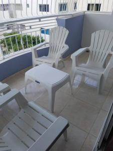 três cadeiras brancas e uma mesa na varanda em SFM-3 Big bedrooms, Wifi, AC/TV & hot water em San Francisco de Macorís