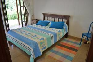 a bedroom with a bed with blue pillows and a chair at Finca Milandia in Villeta