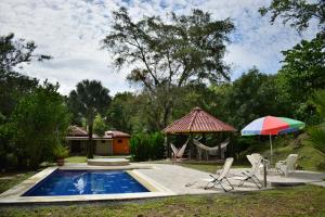 a pool with two chairs and an umbrella and a swing at Finca Milandia in Villeta