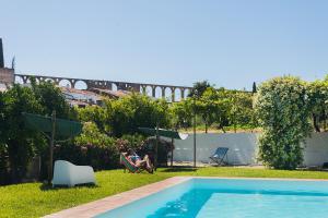 a couple sitting in a chair next to a swimming pool at Horta das Laranjas in Serpa