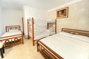 pokój z 2 łóżkami i krzesłem w obiekcie Hotel Ayenda Republicano Colonial No 2 w mieście Santa Marta