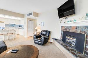 a living room with a fireplace with a television above it at Sand & Sea: The Holladay (418) in Seaside