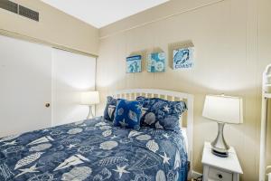 a bedroom with a bed with a blue and white comforter at Sand & Sea: The Holladay (418) in Seaside