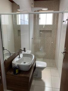 a bathroom with a sink and a toilet and a shower at Ocean Residence in Palhoça