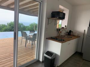 uma cozinha com uma varanda com uma mesa e uma televisão em Kaz Caraibes Bouillante em Bouillante