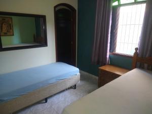 a bedroom with two beds and a mirror on the wall at Casa linda e confortável a 3 min da praia!!! in Peruíbe