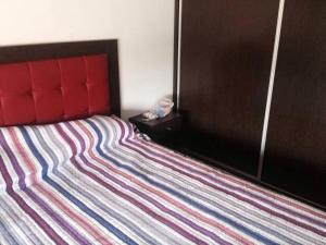 a bed with a red headboard and a striped blanket at LA CASITA in Roldán