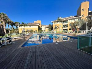 a swimming pool with a wooden deck and buildings at The Sun Full Condominium Resort in Brasília