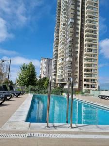 a swimming pool in front of a tall building at Departamento nuevo en sector costa de montemar in Concón
