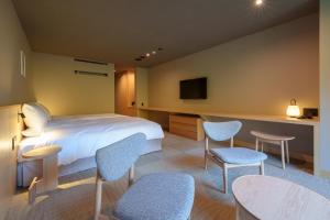 a hotel room with a bed and chairs and a tv at Unzen Miyazaki Ryokan in Unzen