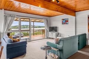 Sala de estar con 2 sofás y TV en Bay Vista Views - Raglan Holiday Home, en Raglan