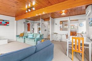sala de estar con sofá azul y mesa en Bay Vista Views - Raglan Holiday Home, en Raglan
