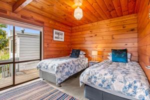 1 dormitorio con 2 camas en una cabaña en Bay Vista Views - Raglan Holiday Home, en Raglan
