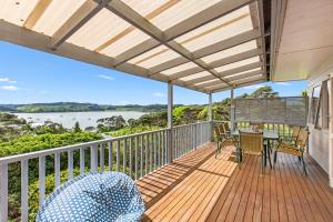 una terraza con mesa y sillas y vistas al agua en Bay Vista Views - Raglan Holiday Home, en Raglan