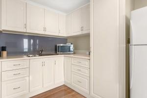 a white kitchen with white cabinets and a microwave at Bayview Unit in Surf Beach