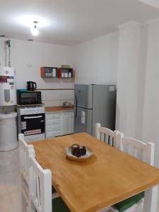 a kitchen with a wooden table and white chairs at Ayres Apart in Chivilcoy +15 photos