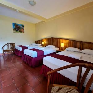 a hotel room with three beds with tables and chairs at Hotel Austria in León