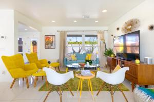 a living room with yellow chairs and a tv at Amarillo House - Luxury Home with Pool & Spa in Palm Springs