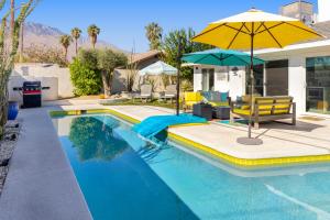 a swimming pool with a yellow umbrella and chairs and a table at Amarillo House - Luxury Home with Pool & Spa in Palm Springs