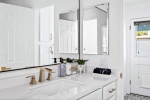 un bagno bianco con lavandino e specchio di The Desert Xscape Pool & Views a Palm Springs