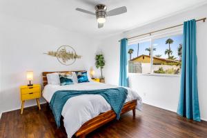 una camera da letto con un letto con tende blu e una finestra di The Desert Xscape Pool & Views a Palm Springs