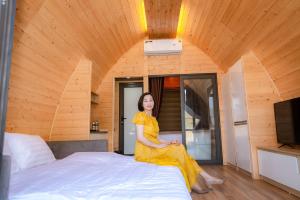 a woman in a yellow dress sitting on a bed at AQUARIUS GARDEN NINH BÌNH in Giá Sơn
