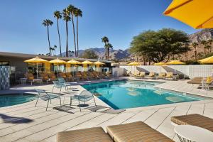 una piscina con sillas y sombrillas en un hotel en Twin Palms Resort - A Gay Men's Resort, en Palm Springs
