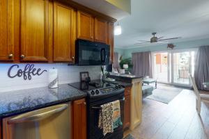 a kitchen with wooden cabinets and a stove top oven at Paradise Shores 107 A Slice of Paradise in Mexico Beach