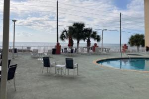 d'une terrasse avec une table et des chaises à côté de la piscine. dans l'établissement Paradise Shores 107 A Slice of Paradise, à Mexico Beach