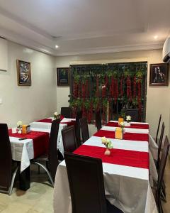 Posh Hotel and Suites Ikeja في إيكيجا: مجموعة من الطاولات في مطعم يحتوي على ملابس مائدة حمراء وبيضاء