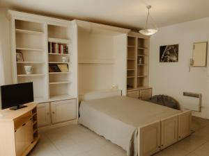a bedroom with a bed and a tv and shelves at Studio Arcachon, 1 pièce, 2 personnes - FR-1-319-42 in Arcachon