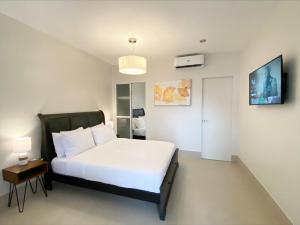 Un dormitorio con una gran cama blanca y una mesa en HARMAN SUITES Moalboal en Moalboal