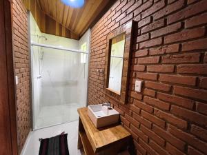 a bathroom with a sink and a brick wall at Chalés Das Estrelas in Visconde De Maua