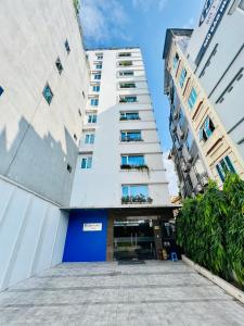 a tall white building with a blue door at HANA Stay Riverside in Hanoi