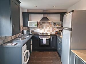 a kitchen with black cabinets and a stainless steel refrigerator at Driftmark Aberavon Beach The Crownlands 4 bedrooms Large Driveway parking 2 mins from Beach in Port Talbot