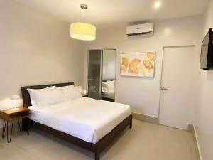 a bedroom with a large white bed and a television at HARMAN SUITES Moalboal in Moalboal